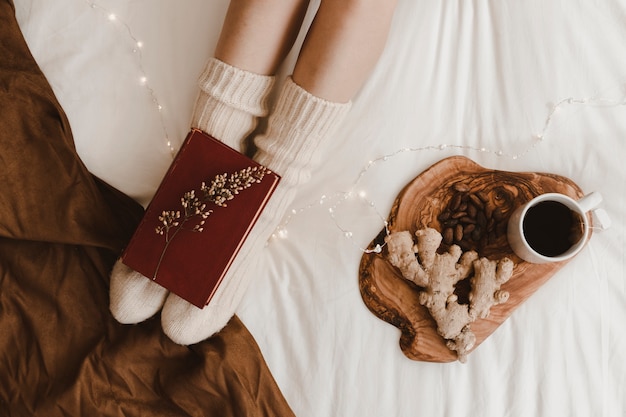 Foto grátis pernas de colheita com livro perto de chá e lanches