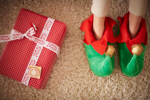 Pernas de Elf ao lado do presente de natal