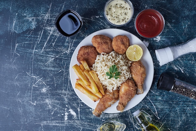 Foto grátis pernas de frango crocantes com palitos de batata e molhos.