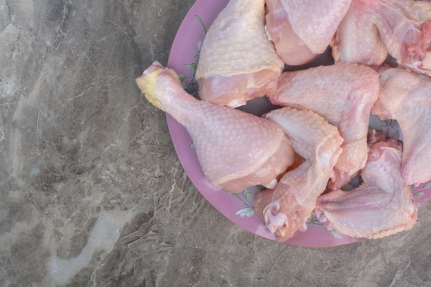 Pernas de frango cruas em prato rosa