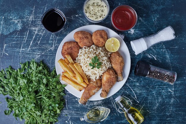 Pernas de frango e batatas fritas com macarrão e molhos.