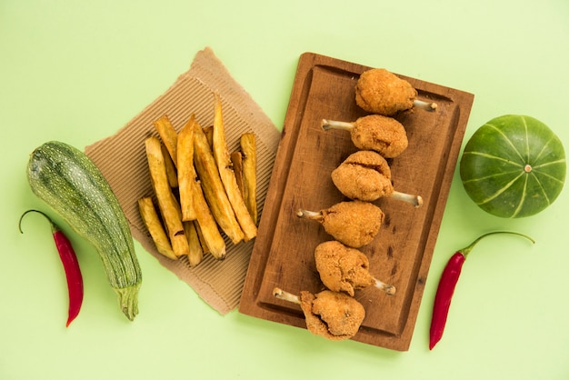 Foto grátis pernas de frango fast-food e batatas fritas, organizando com legumes sazonais