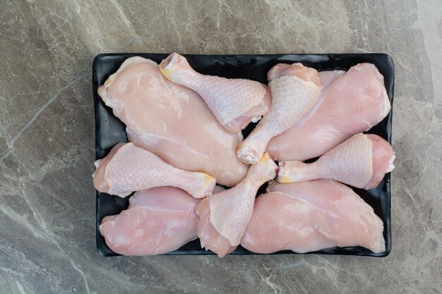 Pernas de frango frescas não preparadas na chapa escura. Foto de alta qualidade