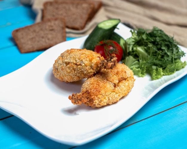 Pernas de frango frito crocantes com salada verde.