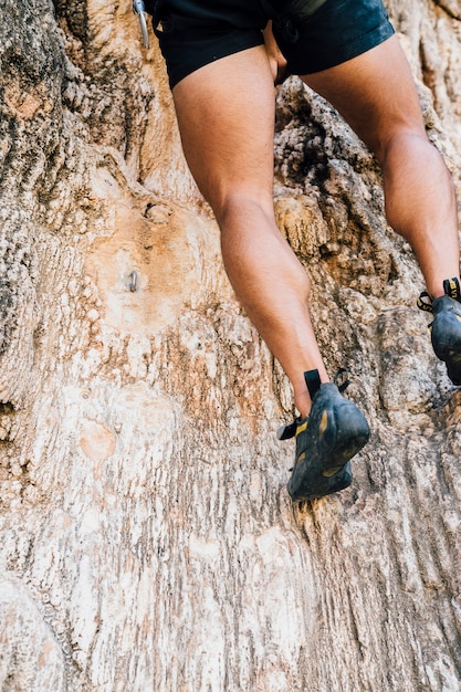 Pernas de homem escalando rock