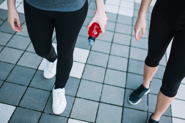 Pernas de mulheres desportivas com bebida vermelha