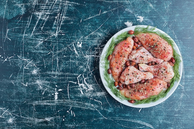 Foto grátis pernas e filé de frango cru em um prato verde.