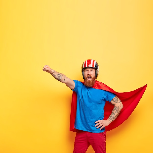 Foto grátis personagem masculino heróico vestido com roupa de super-herói, grita com coragem estou pronto para voar, faz gesto de vôo