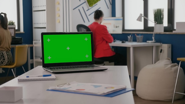 Perto da tela verde no laptop no escritório de negócios. Computador com fundo de chroma key e modelo isolado de simulação na mesa vazia. Espaço de cópia digital de chroma-key em exibição.
