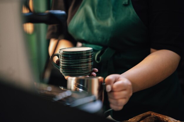 Perto das mãos do barista preparando café para o cliente na cafeteria