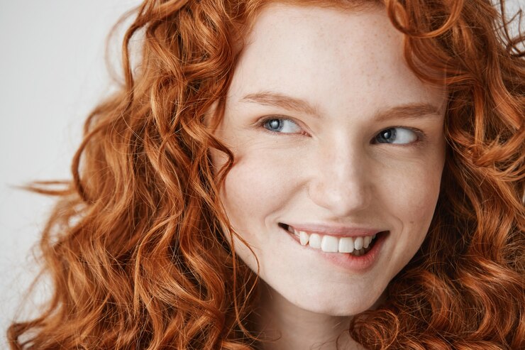 Foto grátis perto de menina bonita com cabelo ruivo cacheado e sardas sorrindo mordendo o lábio.
