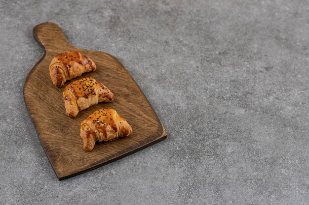 Perto de saborosos biscoitos caseiros em uma tábua de madeira sobre uma superfície cinza