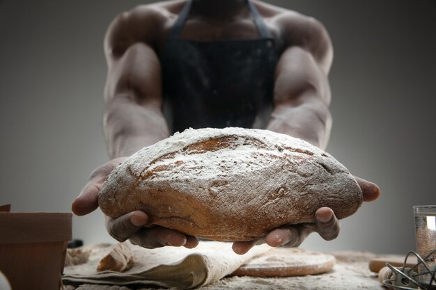 Perto do homem afro-americano cozinha cereal fresco, pão, farelo na mesa de madeira. Comer saboroso, nutrição, produto artesanal