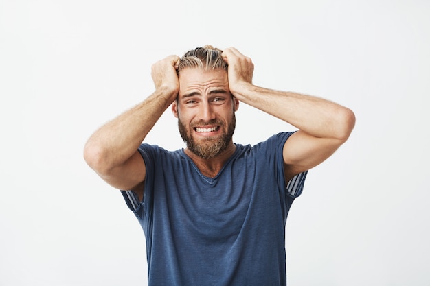 Perto do infeliz bonitão com barba segurando o cabelo com as mãos