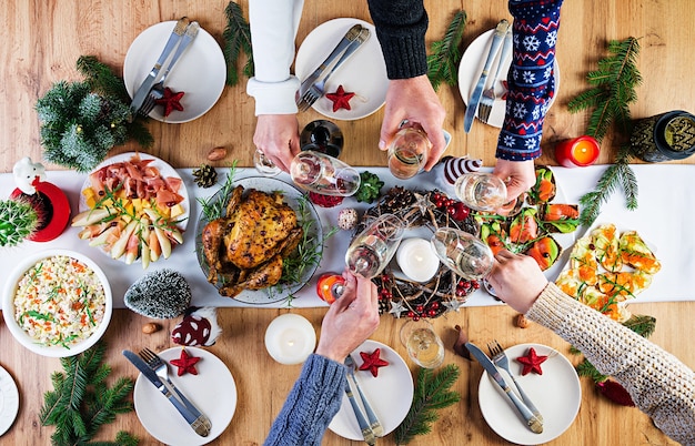 Peru assado. Ceia de Natal. A mesa de Natal é servida com peru, decorada com enfeites brilhantes e velas. Frango frito, mesa. Jantar em família. Vista superior, mãos na moldura