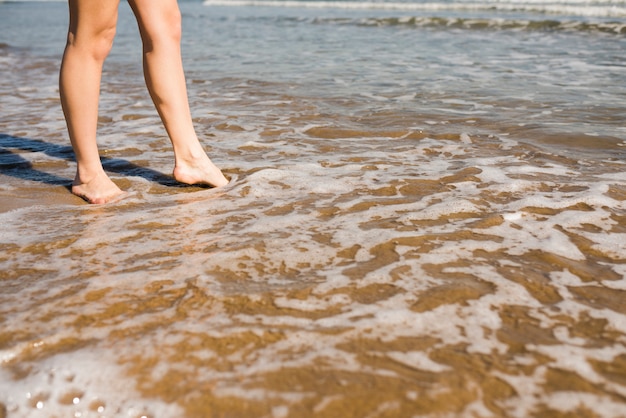 Foto grátis pés descalços da mulher na água do mar rasa na praia