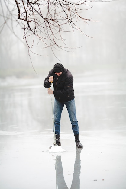 Pesca de inverno no lago congelado com broca de mão