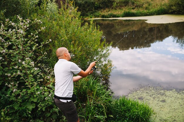 Pescador careca pesca no lago ao ar livre