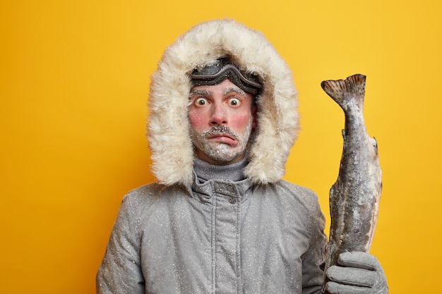 Pescador masculino congelado e perplexo faz expedição de inverno no norte.