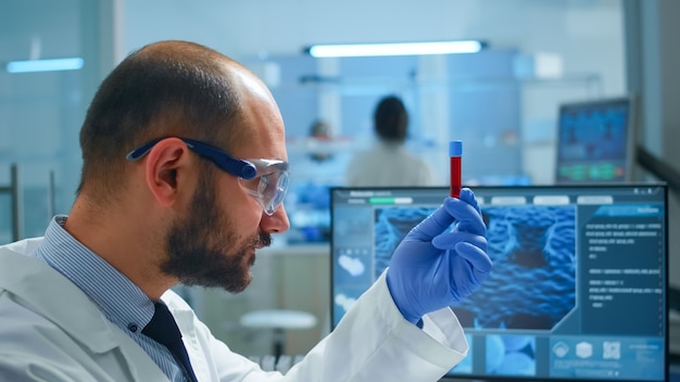 Pesquisador da Viorolog examinando amostra de sangue de tubo de ensaio em um laboratório moderno e equipado