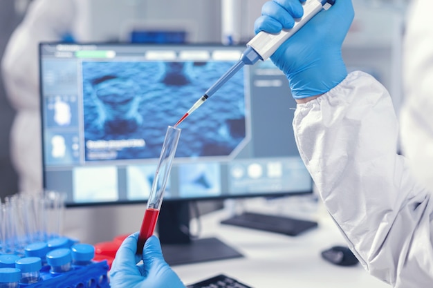 Pesquisador médico pingando sangue em um tubo de ensaio de uma micropipeta. Médico que trabalha com várias bactérias e tecidos, pesquisa farmacêutica de antibióticos contra covid19.