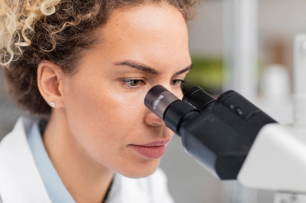 Pesquisadora no laboratório olhando pelo microscópio