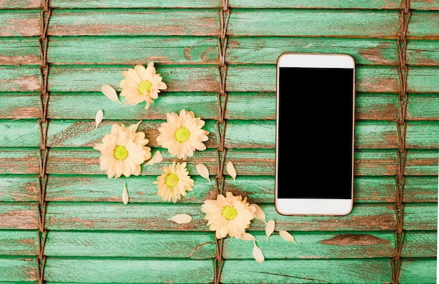 Foto grátis pêssego colorido cabeça de flor e celular no cenário de madeira do obturador