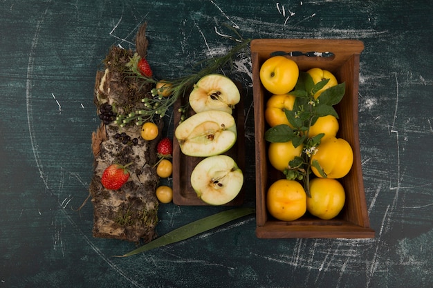 Pêssegos amarelos em uma bandeja de madeira com frutas vermelhas na bandeja