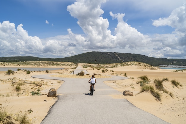 Pessoa a andar de bicicleta por uma estrada rodeada pela praia e pelo mar na Andaluzia, Espanha
