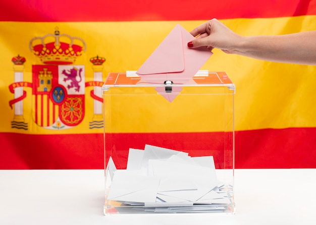 Foto grátis pessoa, colocando um envelope em uma caixa de voto e fundo da bandeira espanhola