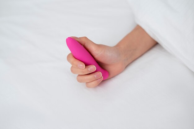 Pessoa com brinquedo sexual na cama