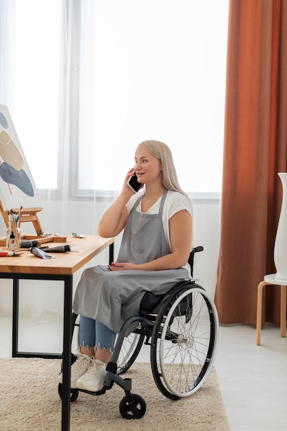Foto grátis pessoa com deficiência em cadeira de rodas usando dispositivo digital