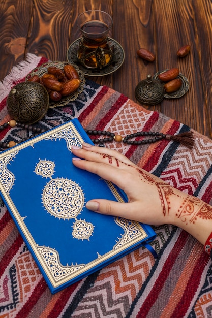 Foto grátis pessoa, com, mehndi, segurando, quran, perto, chá, e, datas, fruta