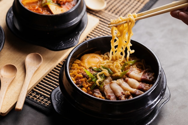 Pessoa comendo comida chinesa em um prato preto com pauzinhos
