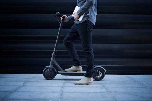 Pessoa de negócios com computador tablet em seu veículo de transporte de scooter elétrico