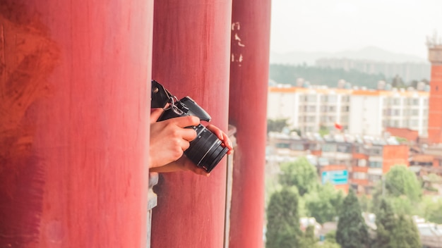 Foto grátis pessoa de pé entre os pilares vermelhos e segurando a câmera