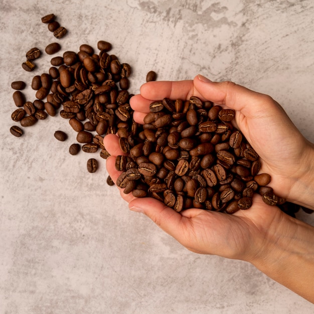 Foto grátis pessoa de vista superior segurando grãos de café torrados