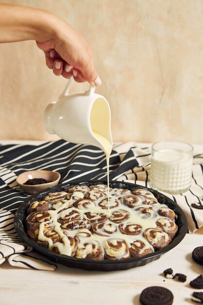 Pessoa derramando o creme branco nos deliciosos pãezinhos de canela