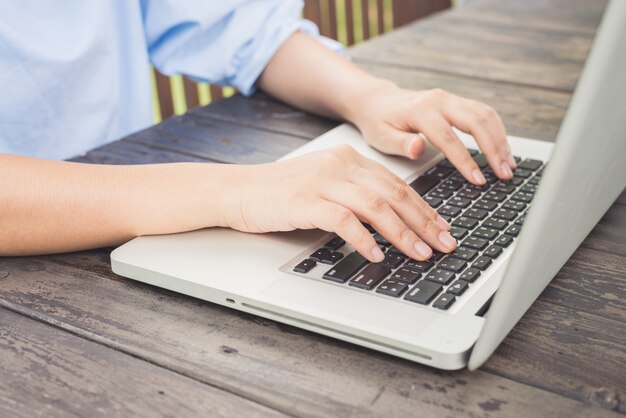 Pessoa digitando em um laptop em uma mesa de madeira