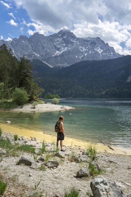 Pessoa em pé na praia do lago Eibsee, na Alemanha, cercada por montanhas