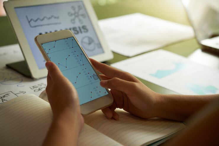 Foto grátis pessoa irreconhecível recortada, analisando o gráfico financeiro no smartphone