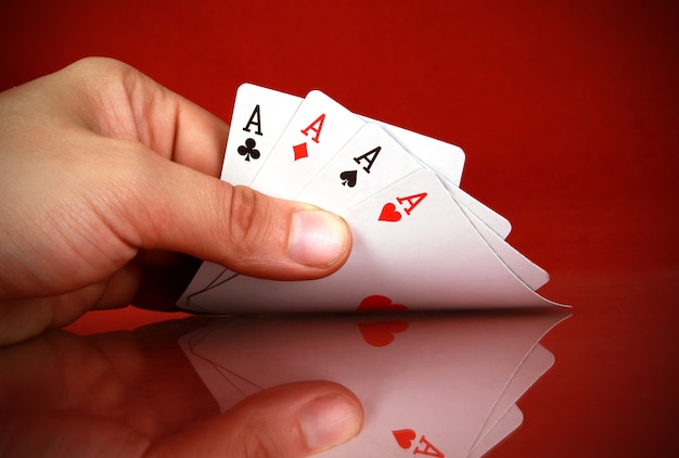 Pessoa jogando cartas com uma quadra na mão