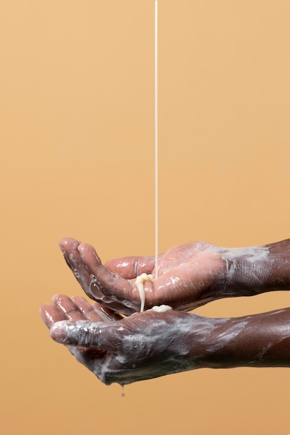 Pessoa lavando as mãos com sabonete isolado em laranja