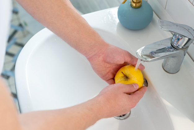 Foto grátis pessoa, lavando, um, maçã amarela, vista alta