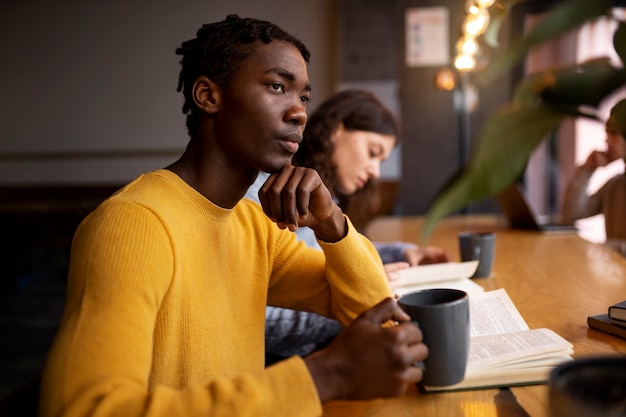 Foto grátis pessoa lendo um livro em um café