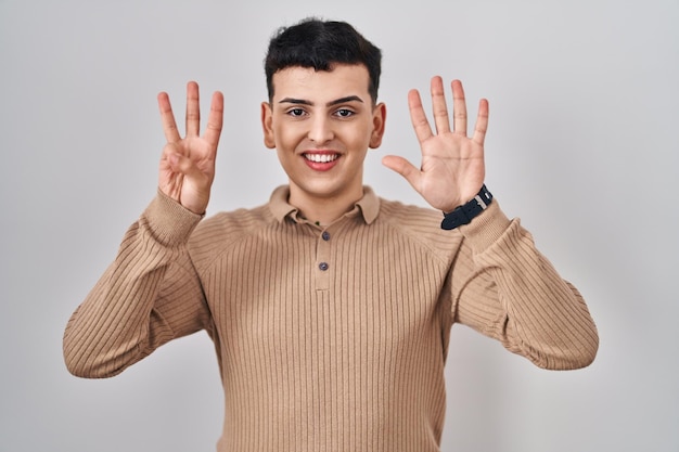 Foto grátis pessoa não binária em pé sobre fundo isolado mostrando e apontando para cima com os dedos número oito enquanto sorria confiante e feliz