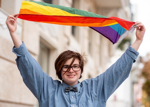 Pessoa não binária segurando a bandeira lgbt