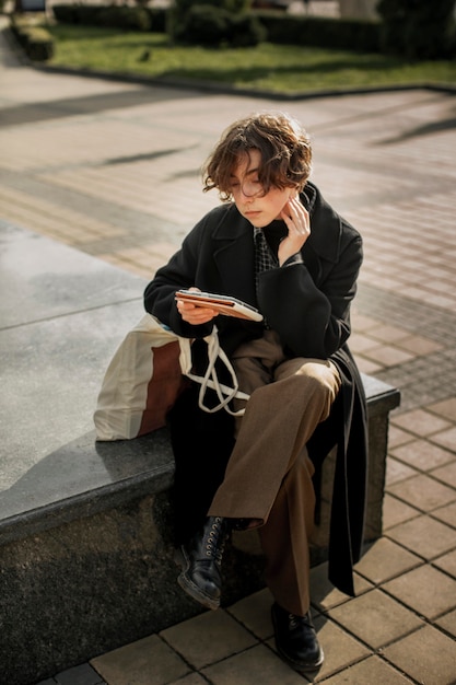 Pessoa não binária sentada e olhando para um tablet