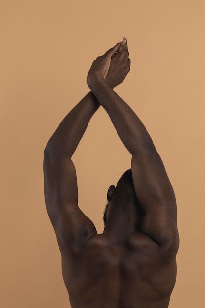 Pessoa negra nua com as mãos para cima por trás da foto