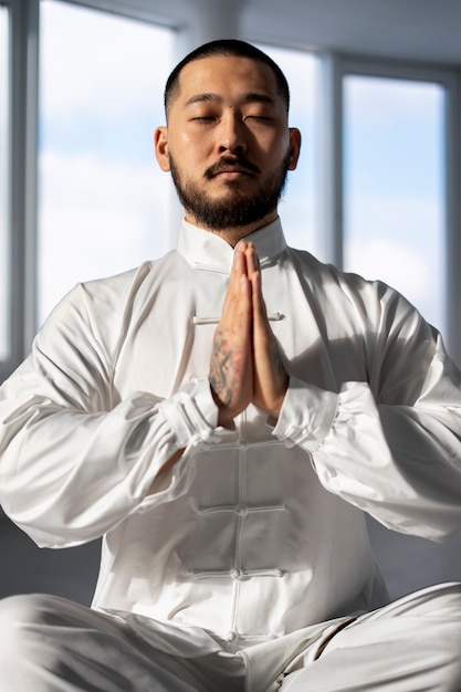 Foto grátis pessoa praticando tai chi dentro de casa